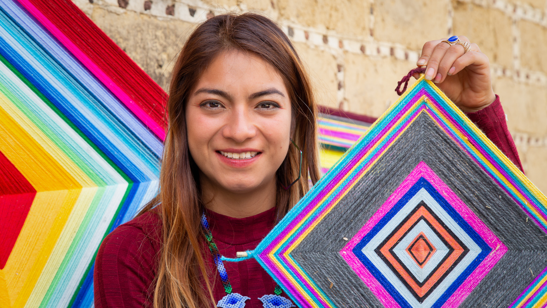 woman holding colorful huichol ojos de dios folk art