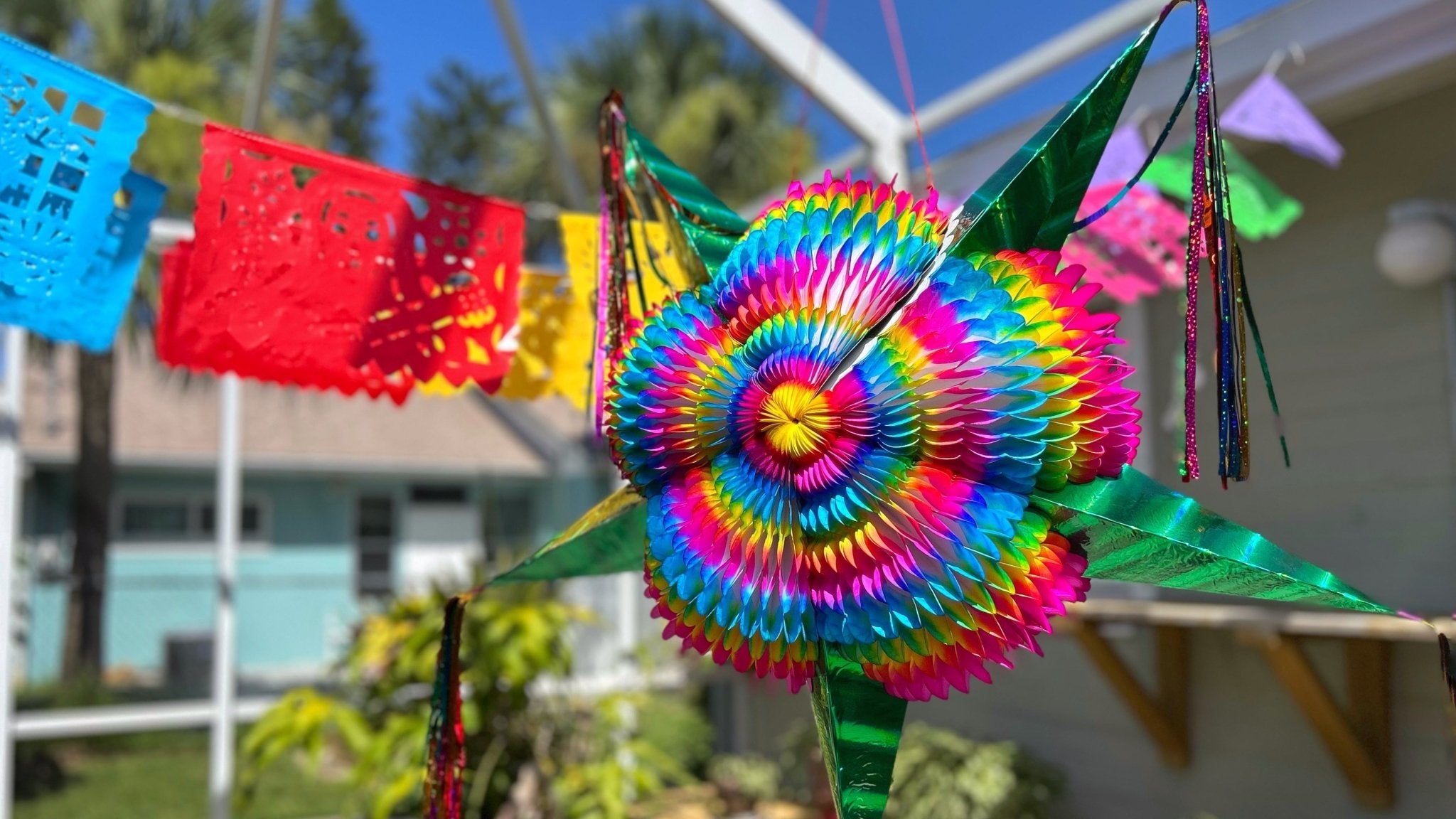 colorful papel picado banners outside with large green star pinata