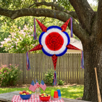 Decorative paper piñata with red, white, and blue colors hanging from a tree branch outdoors.