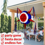Red, white, and blue star-shaped piñata hanging from a porch with people sitting at a table below.