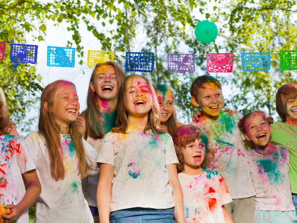Children with paint on their faces outdoors under colorful flags