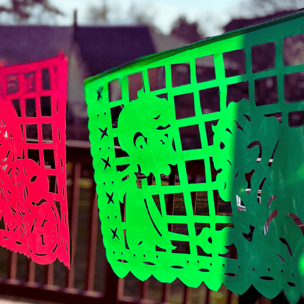 Colorful papel picado banners hanging against a blurred outdoor background